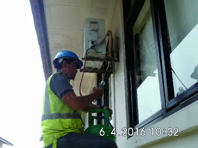 Teknisi memeriksa unit outdoor AC di dinding luar gedung